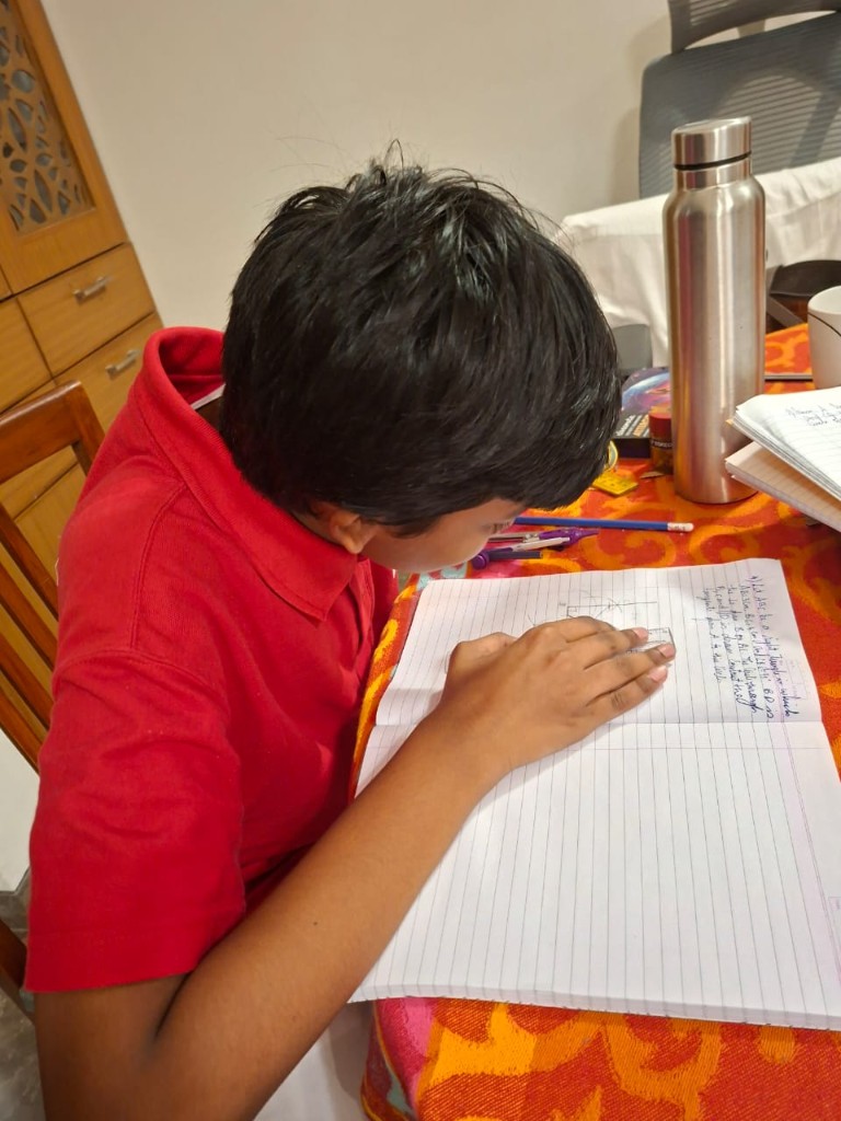 Young student in a red polo working on geometry diagrams in a spiral notebook at a home study table