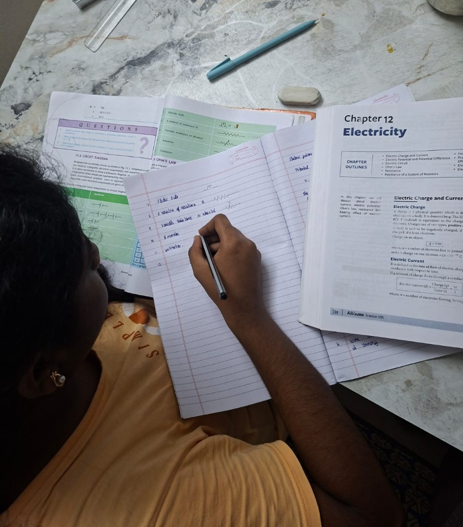 Student writing electricity circuit symbols in a notebook beside open Class 10 science textbooks